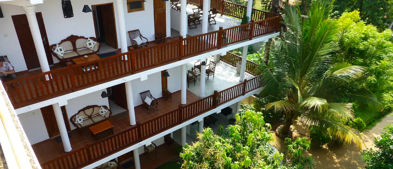 Elegant wooden balconies of a tropical hotel nestled among lush green trees in Unawatuna, Sri Lanka.