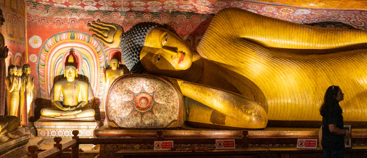 A person views the majestic golden reclining Buddha statue inside the ancient Dambulla Cave Temple.