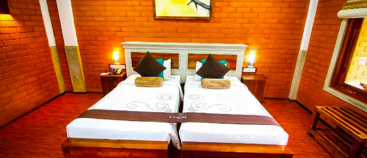 A comfortable hotel room featuring two single beds, brick walls, and warm lamps in Dambulla.