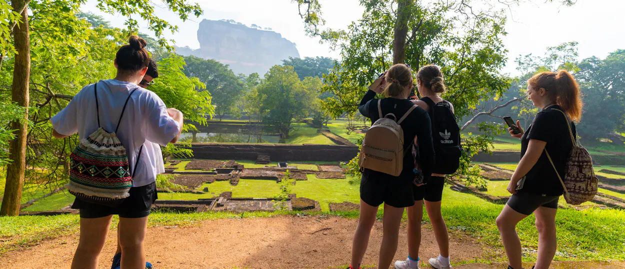 Four backpackers admire the ancient water gardens and majestic Sigiriya Rock in Sri Lanka.