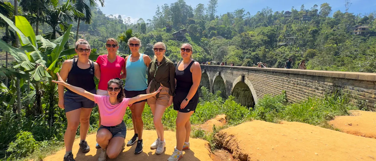 Six happy women posing in front of the historic Nine Arch Bridge in Ella, Sri Lanka.