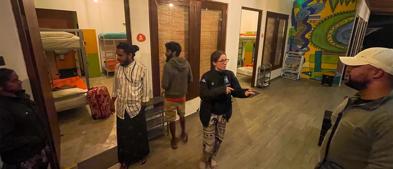 A group of backpackers and locals gather in a hostel common area in Sri Lanka.