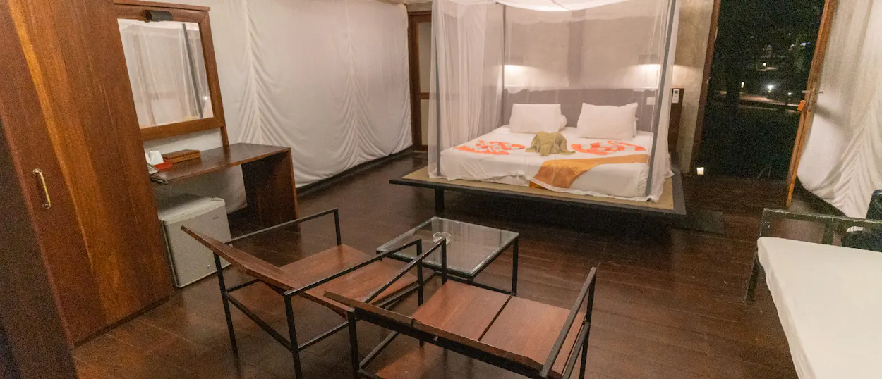 Cozy safari-style room in Udawalawe, Sri Lanka, featuring a mosquito net bed and wooden furniture.