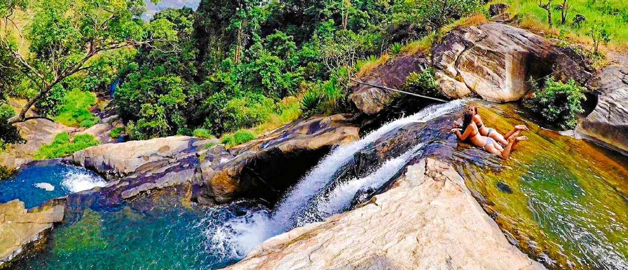 Adventurers relax in natural pools at the top of Diyaluma Falls, overlooking the Sri Lankan jungle.