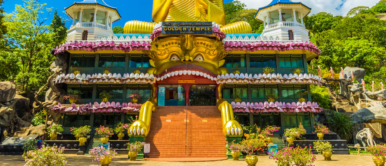 Ornate Golden Temple building with a giant golden face and a reclining Buddha statue in Sri Lanka.