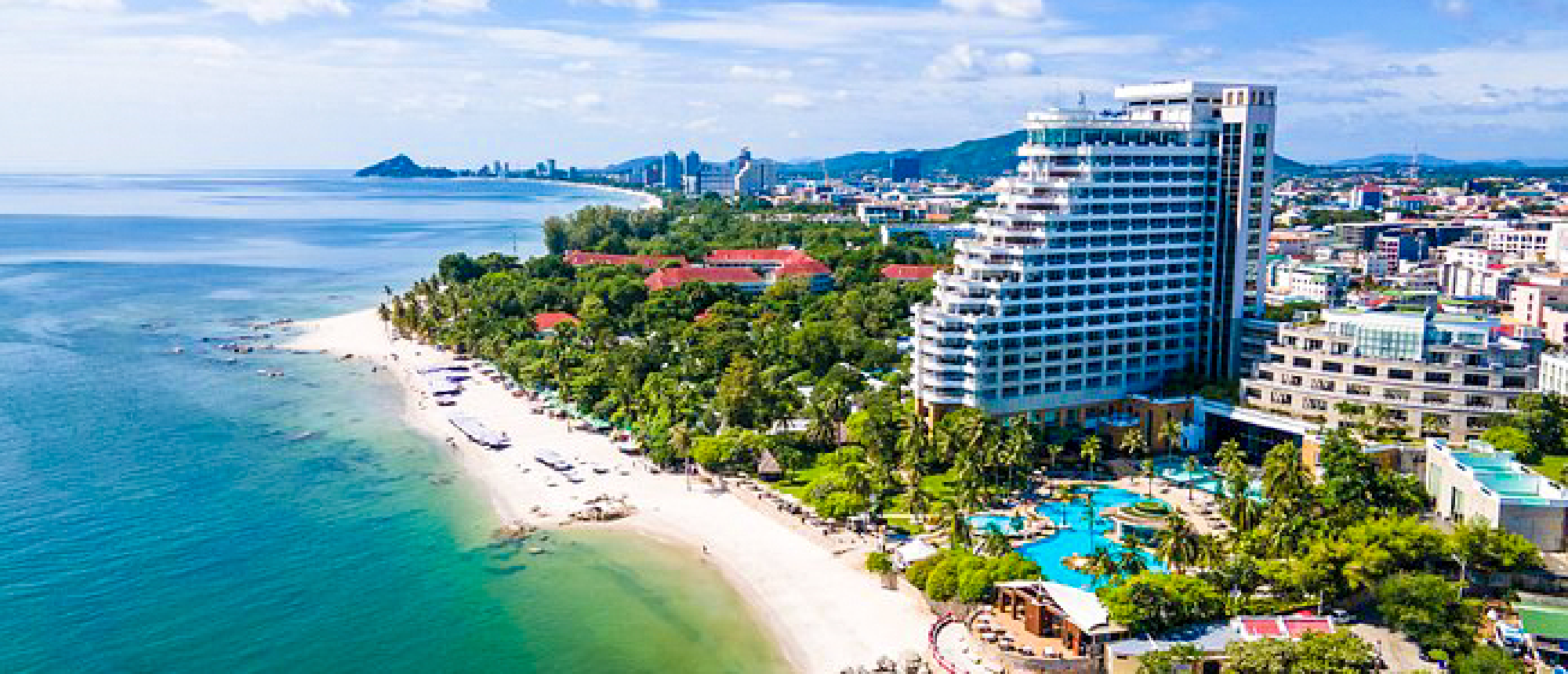 Aerial view of a beautiful sandy beach, turquoise ocean, and modern resorts in Hua Hin, Thailand.
