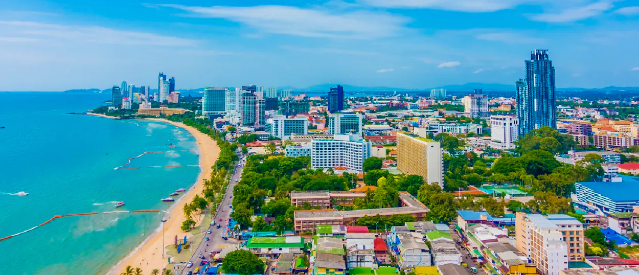 Vibrant coastal city with a long sandy beach, turquoise water, and many buildings.