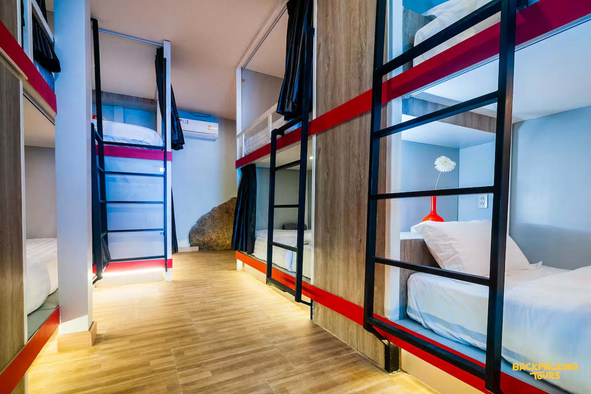 A modern hostel dorm room with comfortable bunk beds and privacy curtains on Koh Phangan.