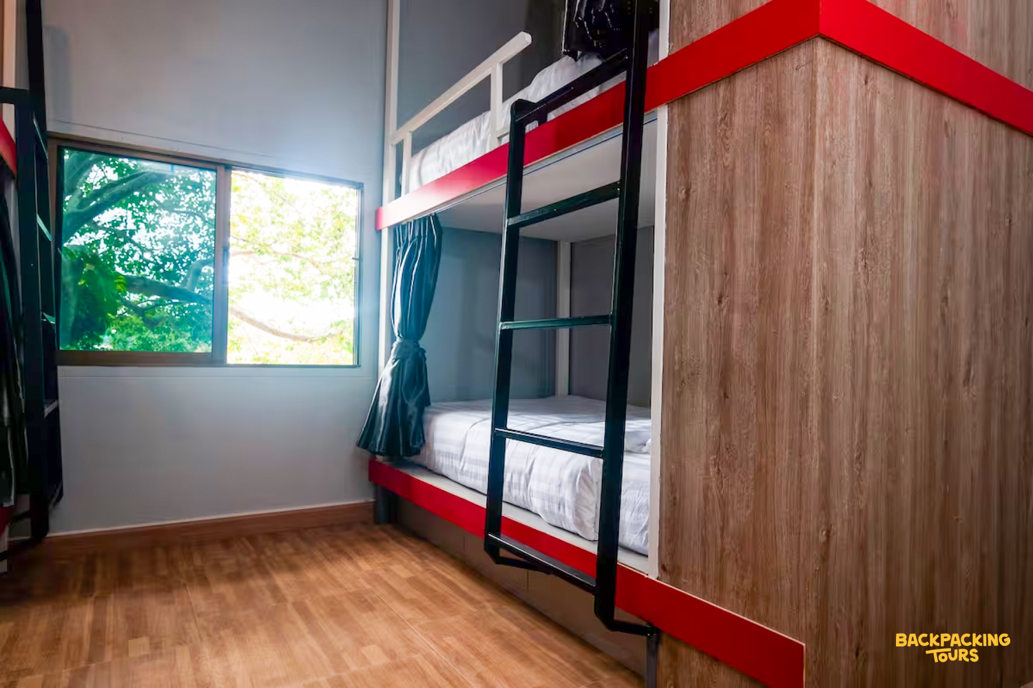 Clean and modern hostel room on Koh Phangan with wooden bunk beds and a window.