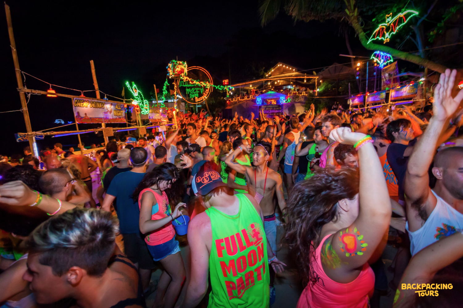 Energetic partygoers dance under vibrant neon lights at the famous Full Moon Party on Koh Phangan.