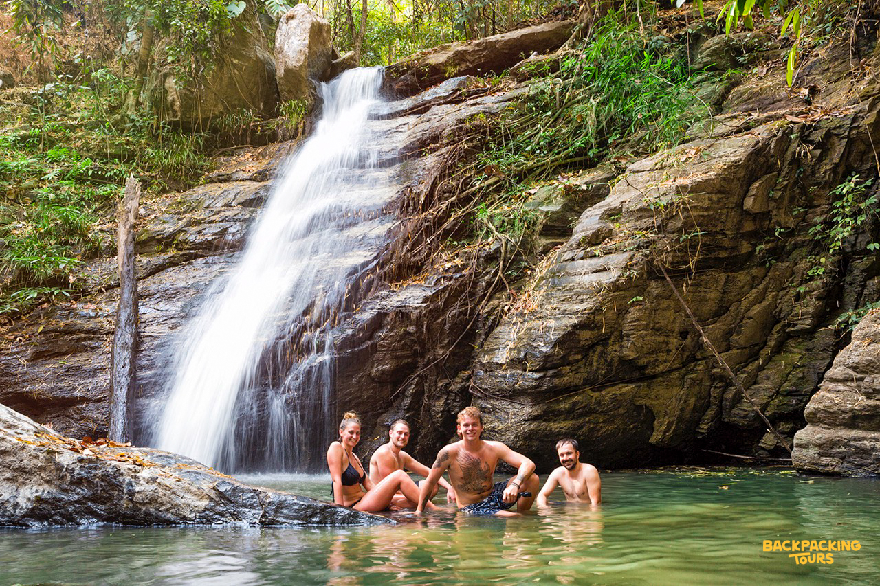 Four backpackers happily cool off in the refreshing waters of a waterfall near Chiang Mai.