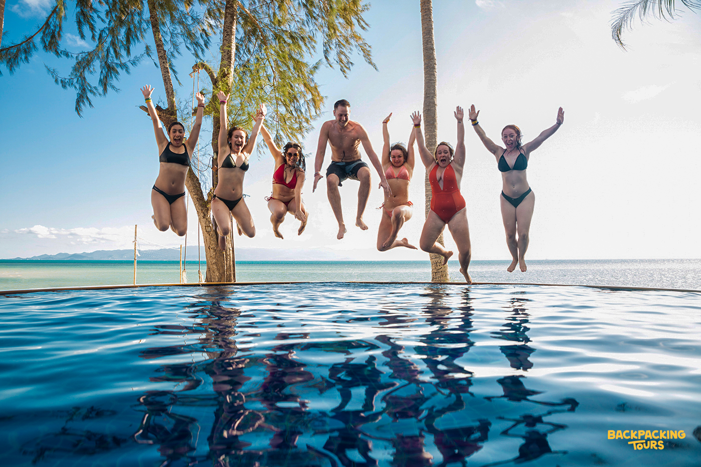 Friends jumping into a pool at a tropical resort on Koh Phangan during a fun day of swimming on the backpacking tour