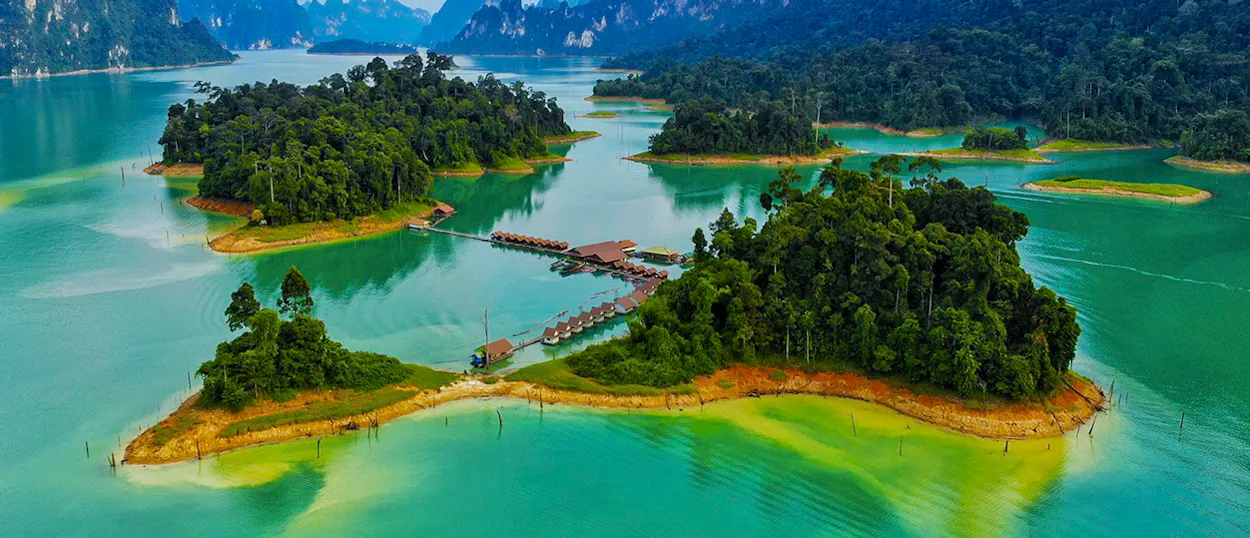 Floating bungalows nestled among lush green islands on the emerald waters of Khao Sok Lake, Thailand.