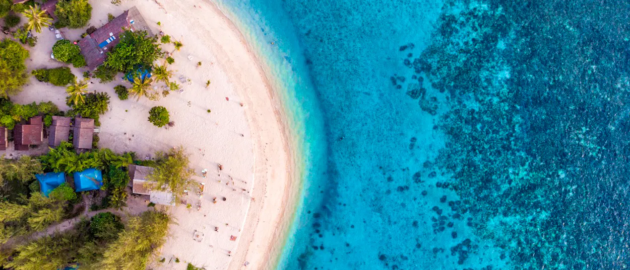 Aerial view of Koh Phangan's pristine white sand beach meeting crystal-clear turquoise ocean waters.