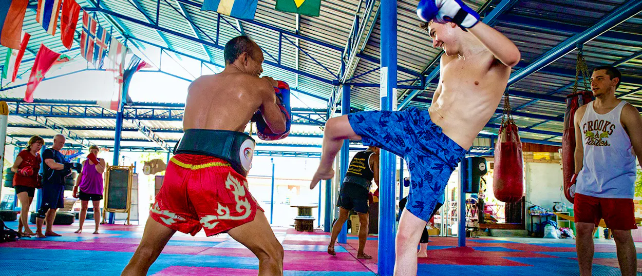 A student practices a high kick with an instructor during a Muay Thai class in Koh Phangan.