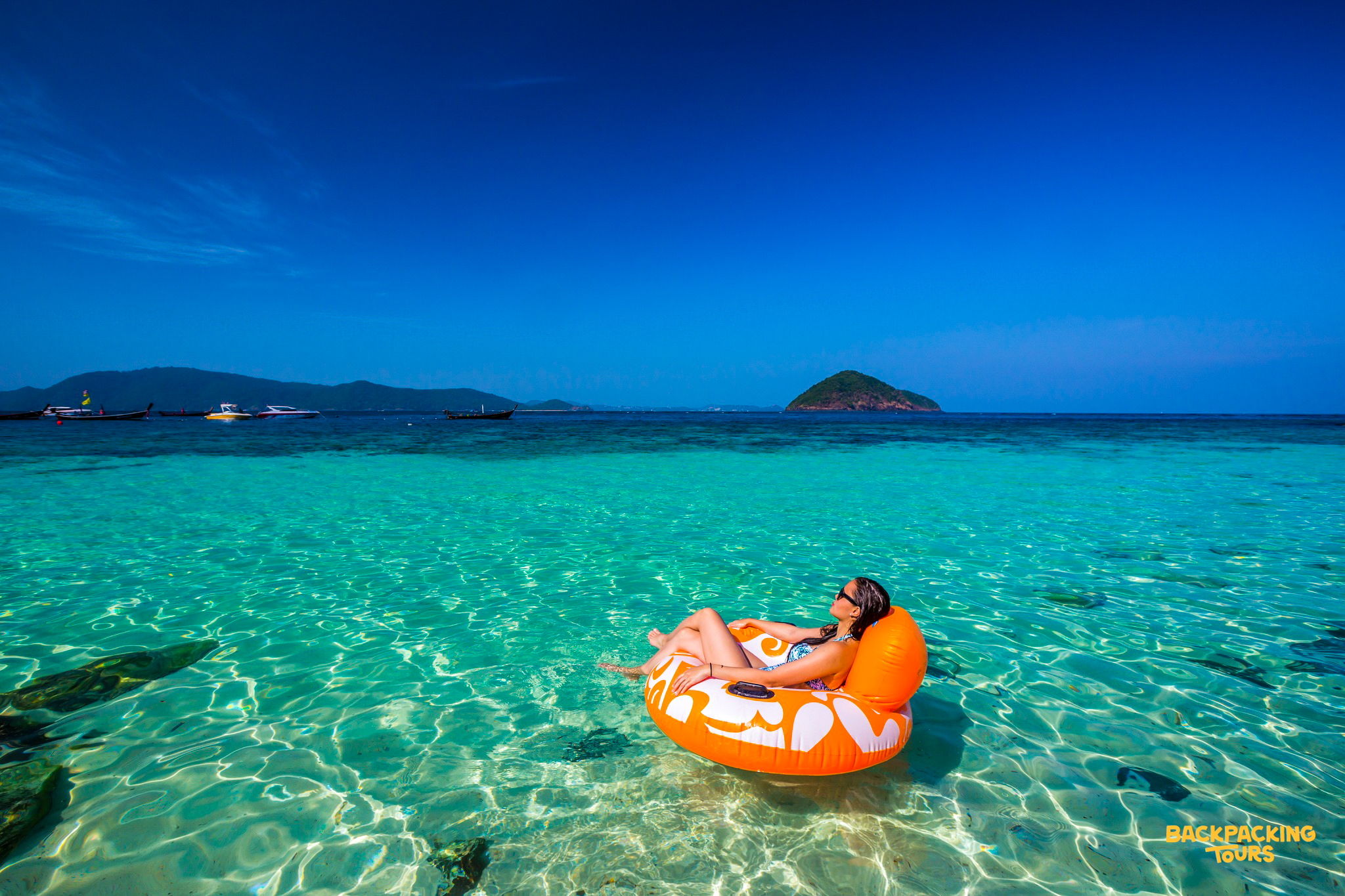 Relaxing on an orange float in the clear turquoise waters of Phuket under a bright blue sky.