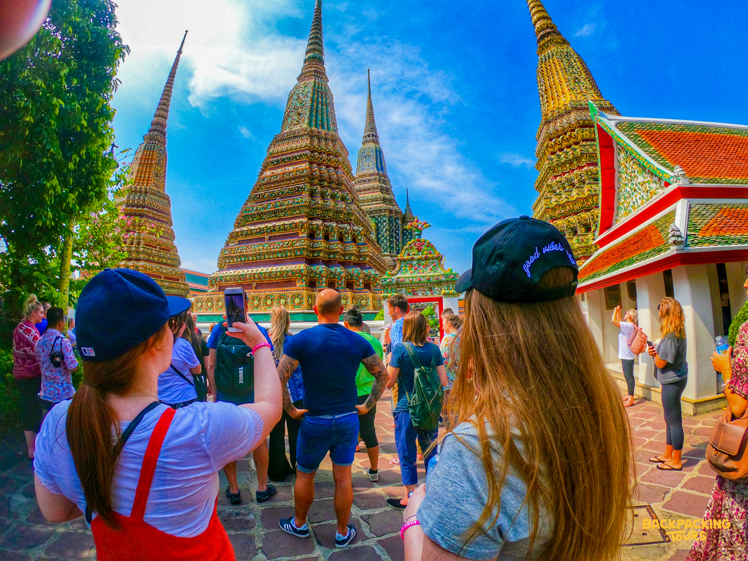 Tourists admire the ornate golden stupas and colorful temple architecture at Wat Pho in Bangkok.