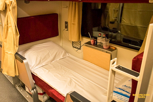 Sleeper cabin on a train departing from Bangkok, offering a comfortable bed for an overnight journey.