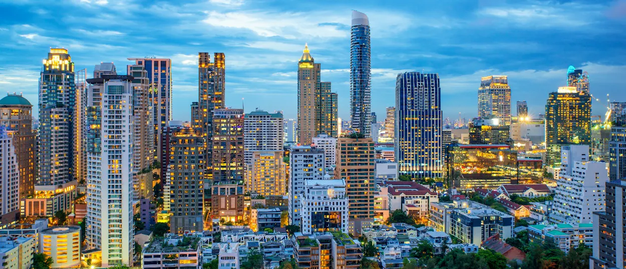 Illuminated skyscrapers dominate the Bangkok city skyline at dusk, showcasing the bustling capital.