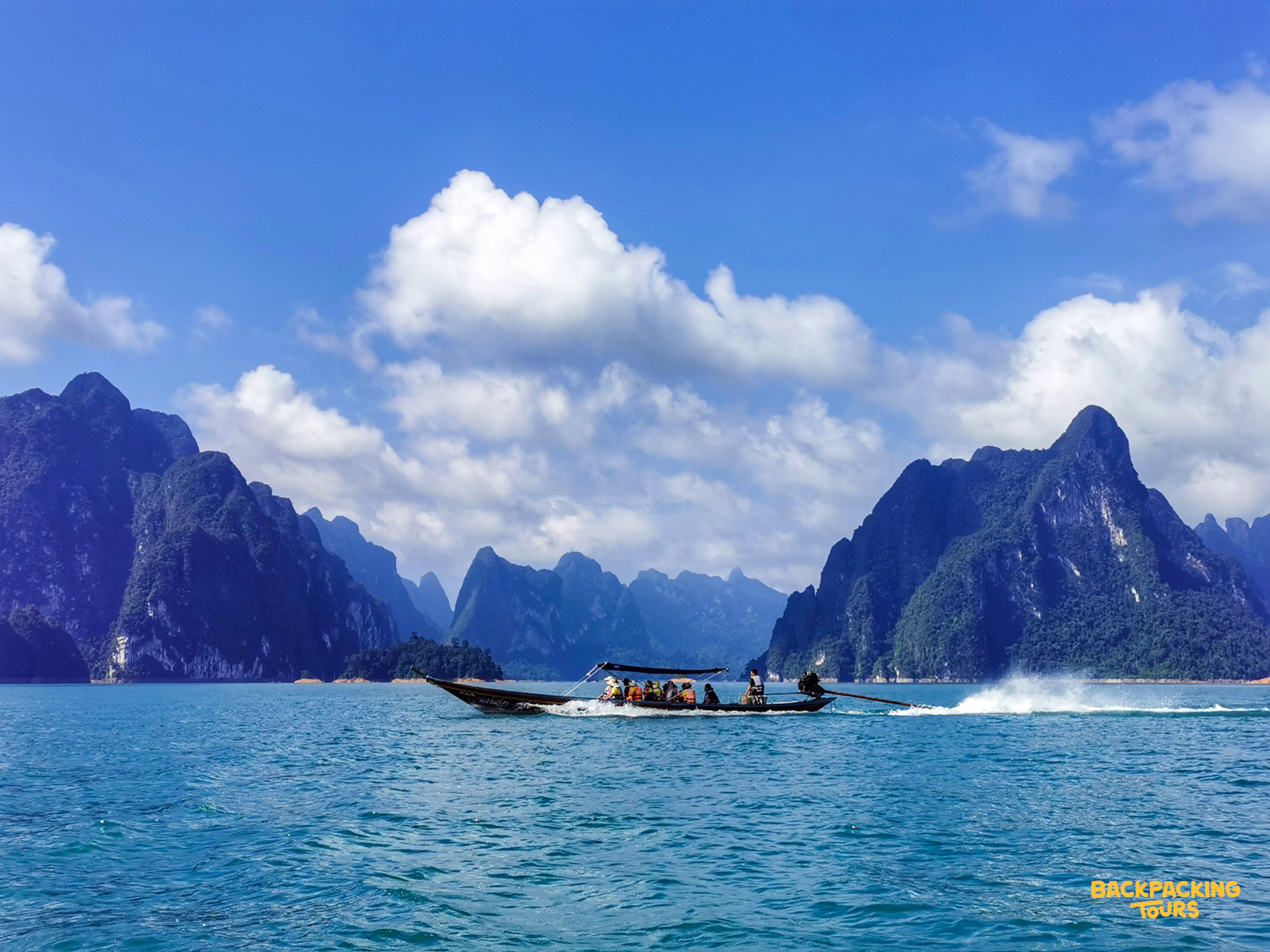Tourists enjoy a scenic longtail boat ride through the majestic limestone karsts of Khao Sok National Park.