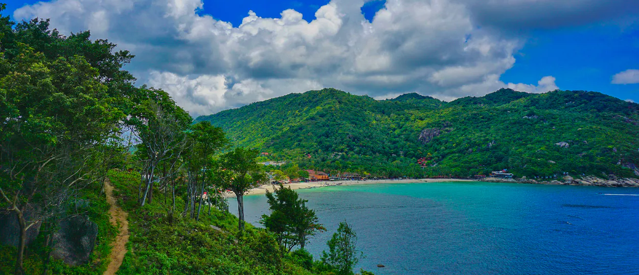 Stunning tropical bay with green hills, a sandy beach, and clear blue water on Koh Phangan.