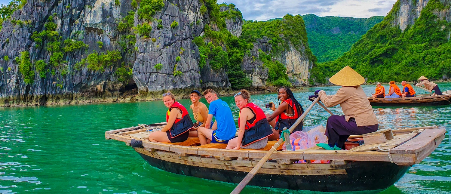Tourists in life vests enjoy a boat ride through the stunning limestone karsts of Halong Bay.