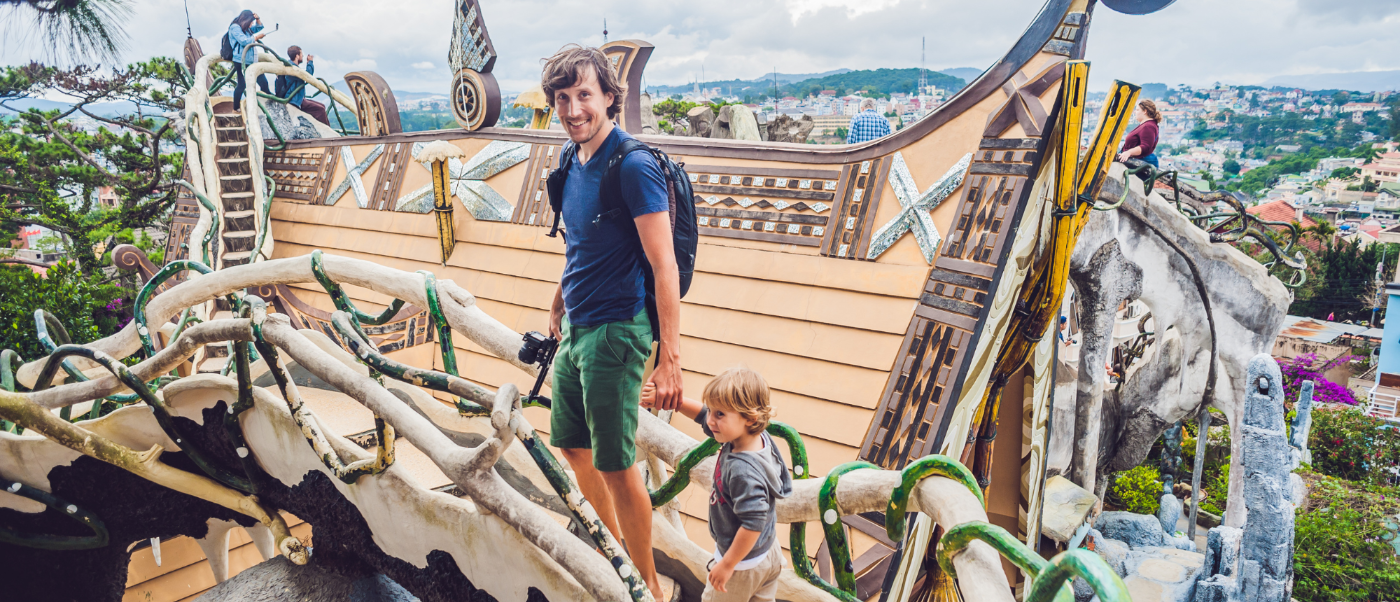 A man and child smile while exploring the whimsical architecture of the Crazy House in Dalat.