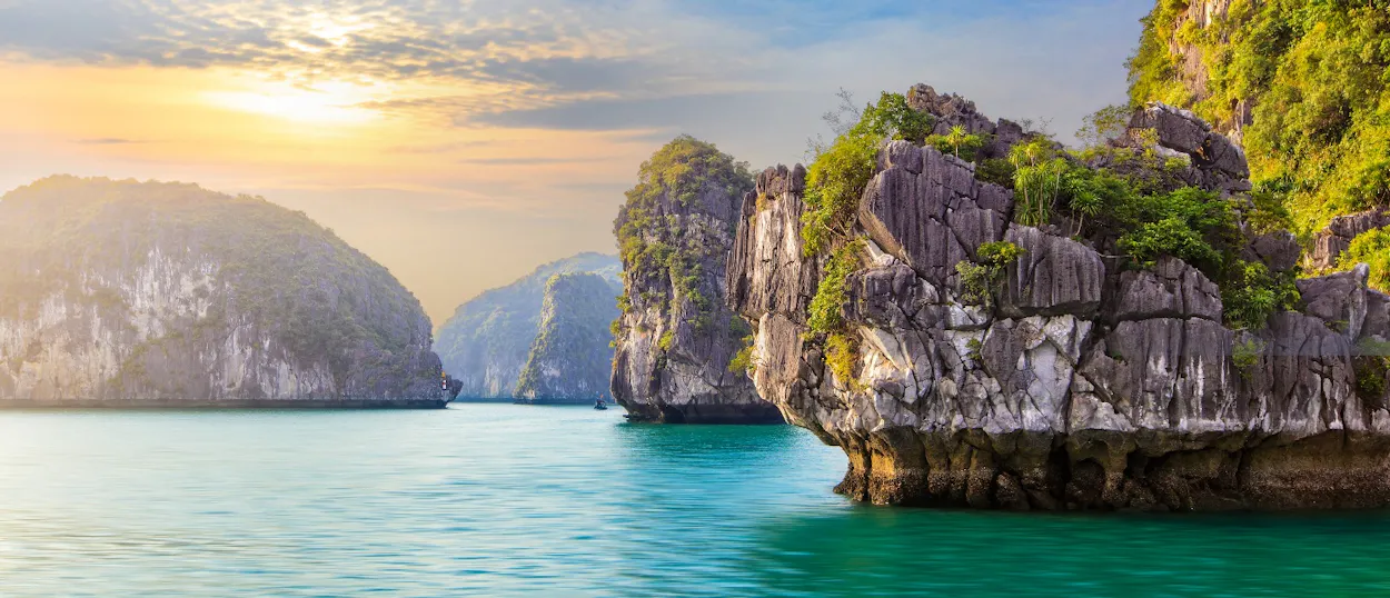 Breathtaking Halong Bay at sunset, with towering limestone karsts rising from emerald waters.