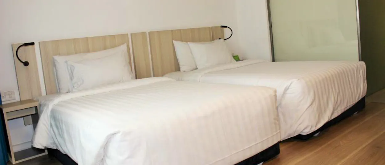 Two neatly made single beds in a bright, minimalist hotel room in Ho Chi Minh City.