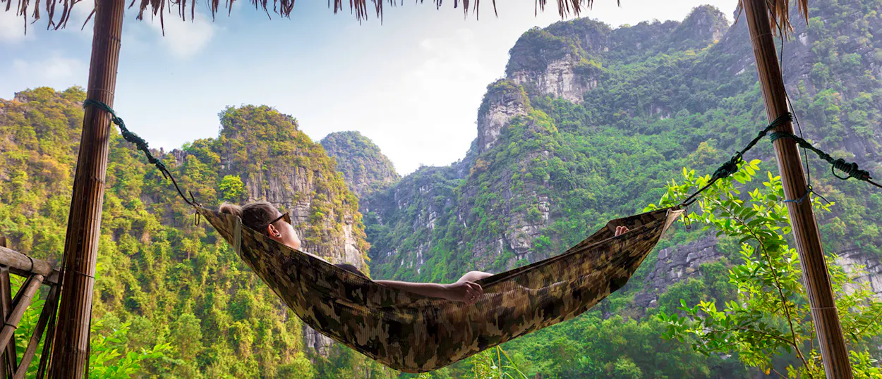 A traveler enjoys a peaceful moment in a hammock amidst the stunning limestone karsts of Ninh Binh.