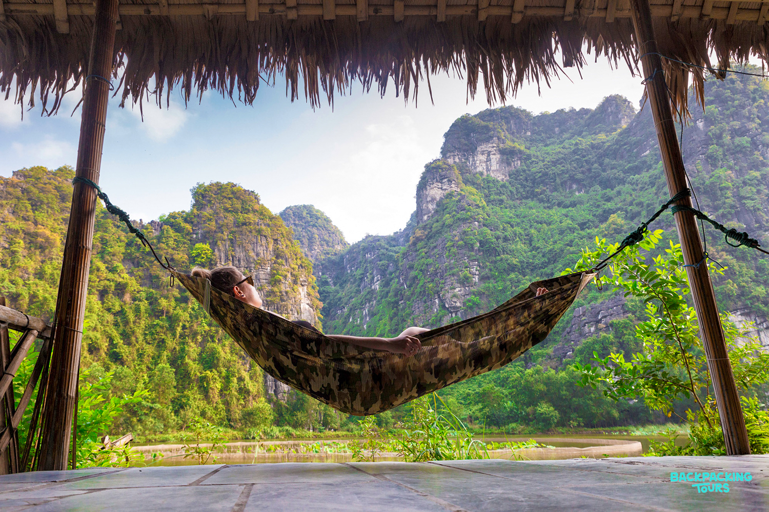 Relaxing in a hammock at a Ninh Binh homestay, enjoying views of dramatic limestone karsts.