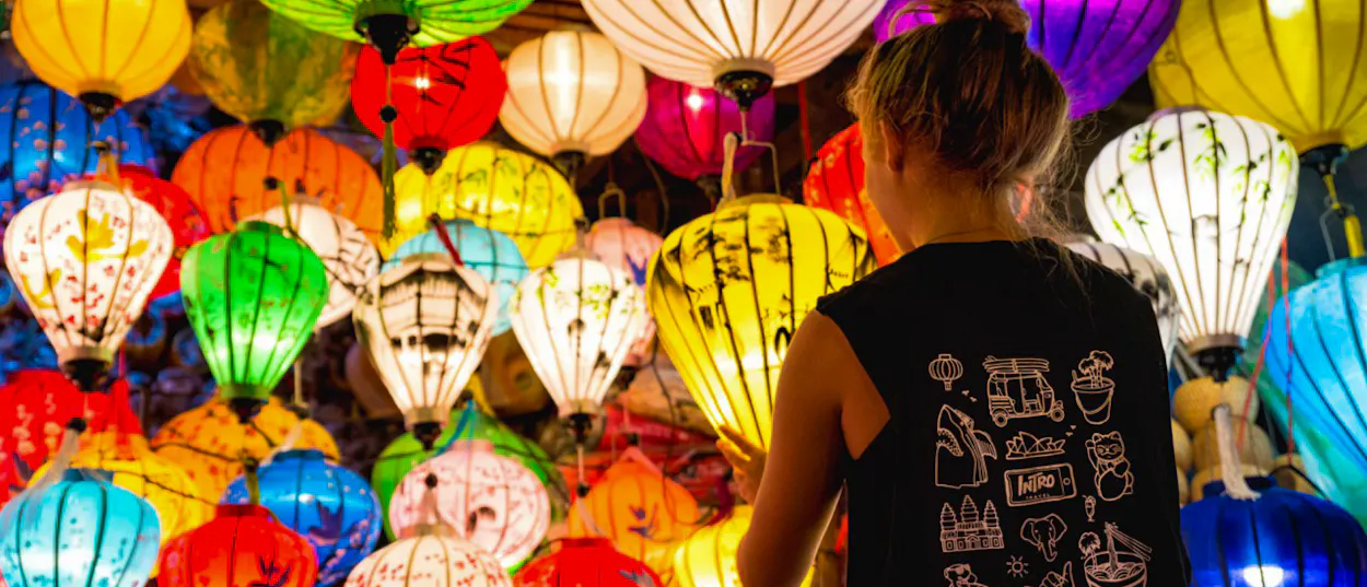 A person views a vibrant display of colorful, illuminated lanterns in Hoi An, Vietnam.