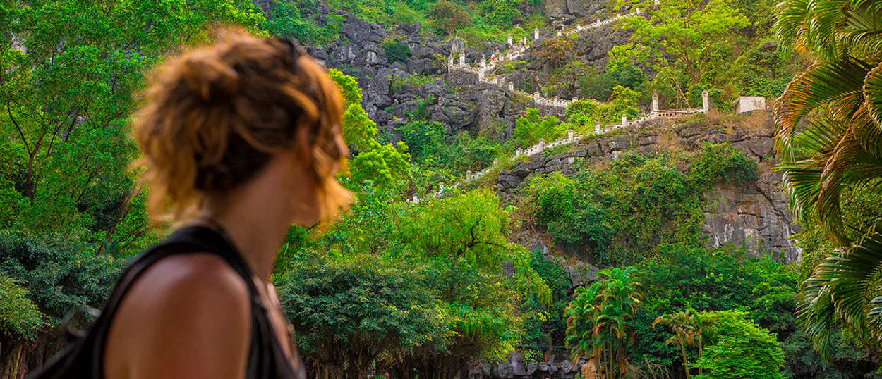 A traveler looks at the winding path up a lush green mountain in Ninh Binh.