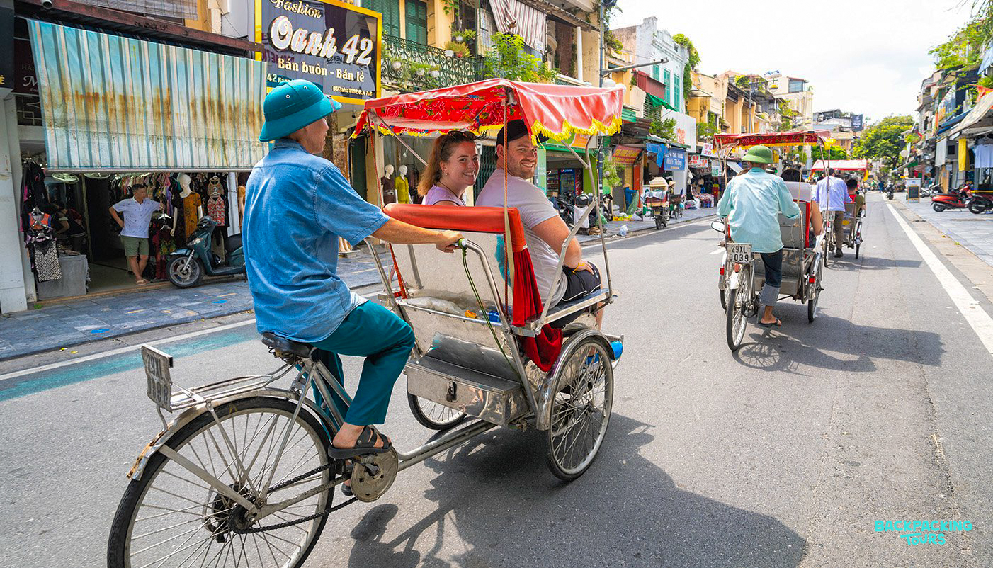 Two travelers enjoy a traditional cyclo ride through the bustling, vibrant streets of Hanoi.