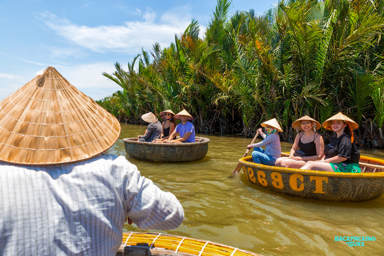 Travelers in conical hats explore the scenic coconut groves of Hoi An by traditional basket boat.