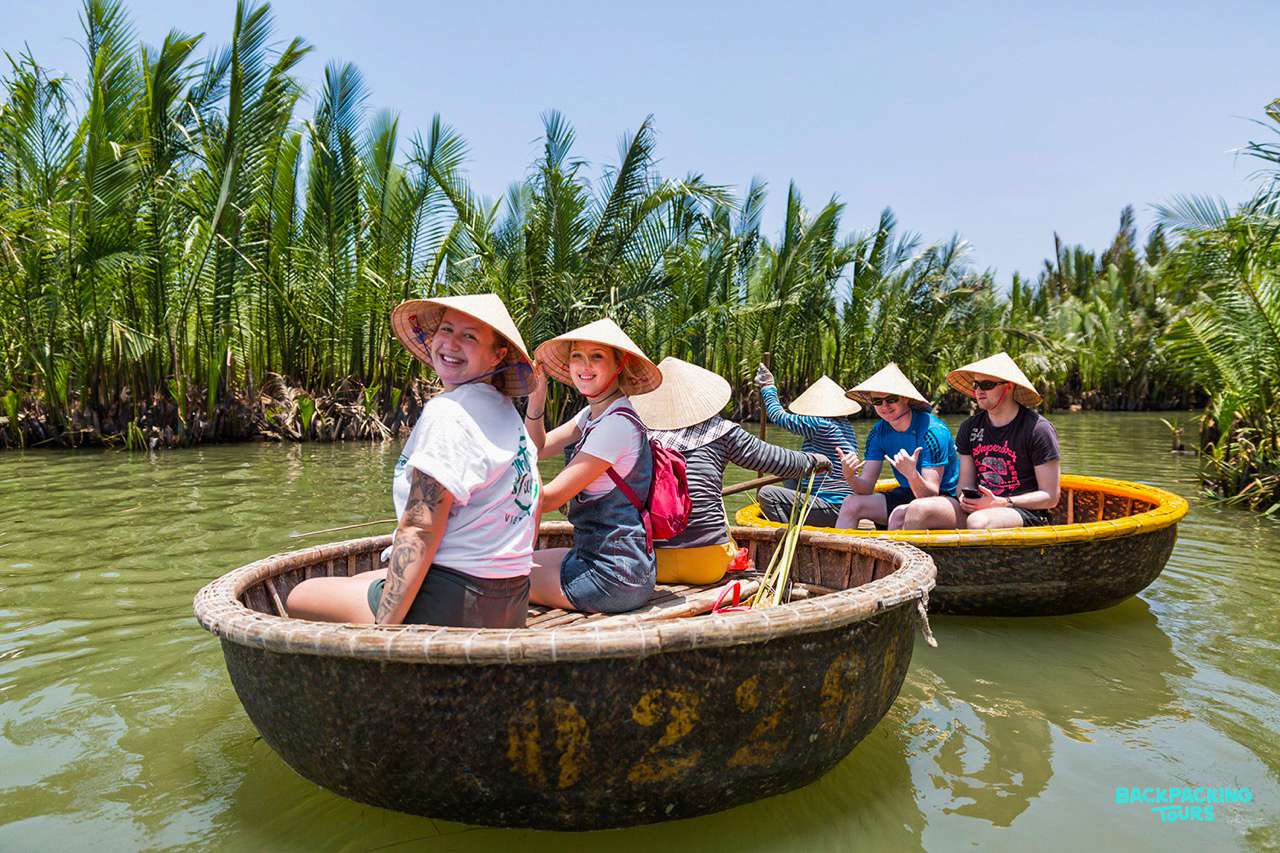Tourists in conical hats enjoy a sunny basket boat ride through coconut groves in Hoi An.