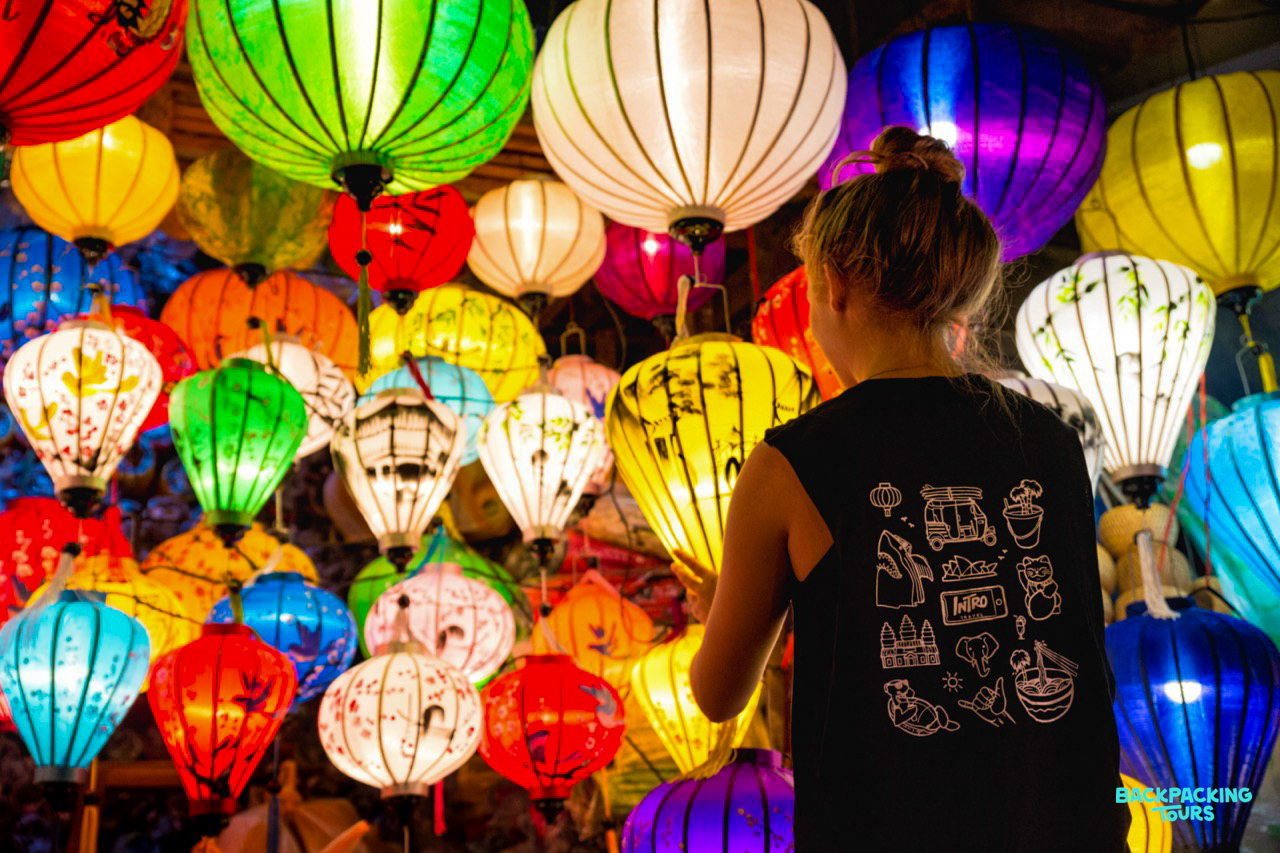 A traveler admires a vibrant display of glowing silk lanterns in Hoi An, Vietnam.