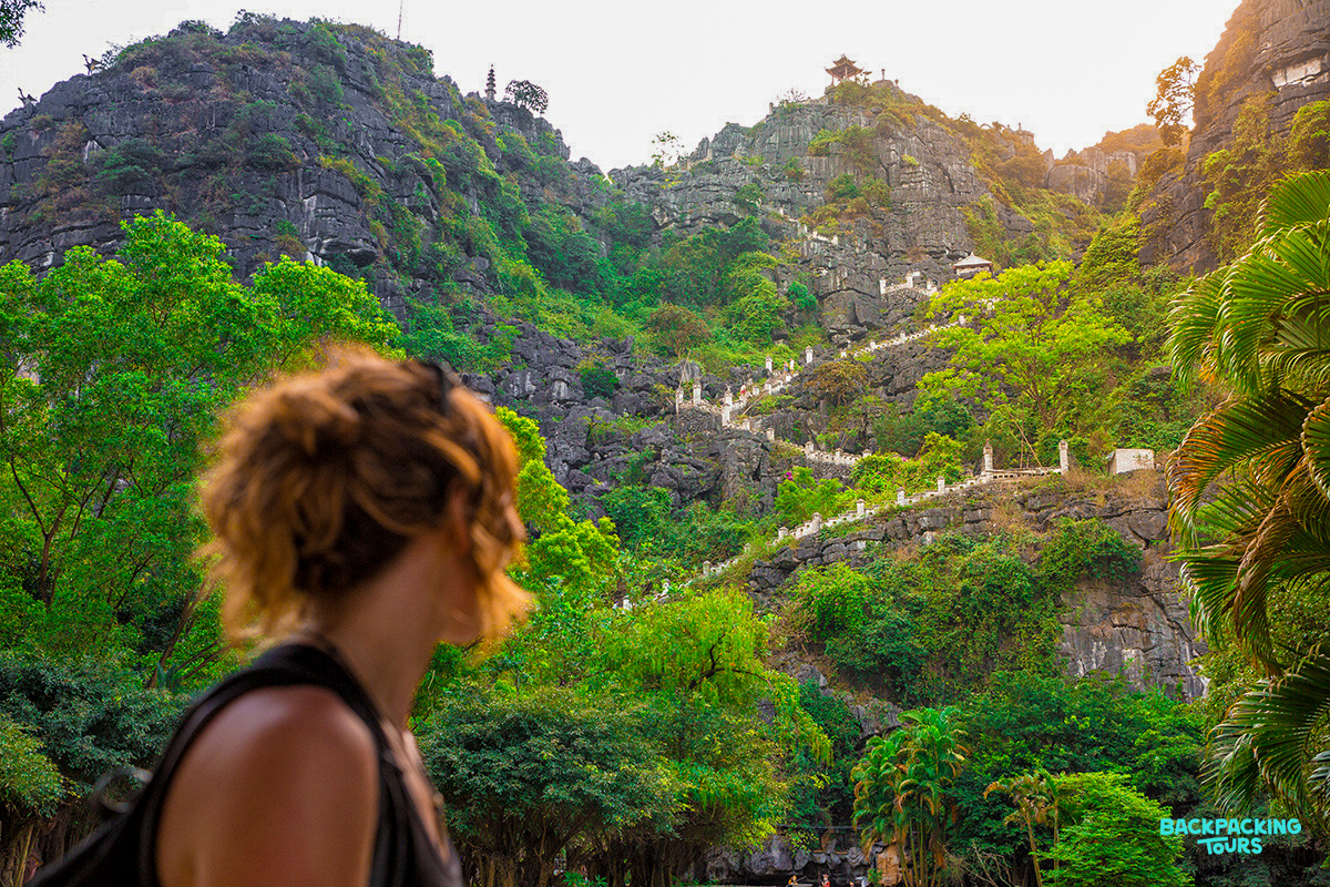 A woman looks towards the majestic limestone mountains and winding steps in Ninh Binh.