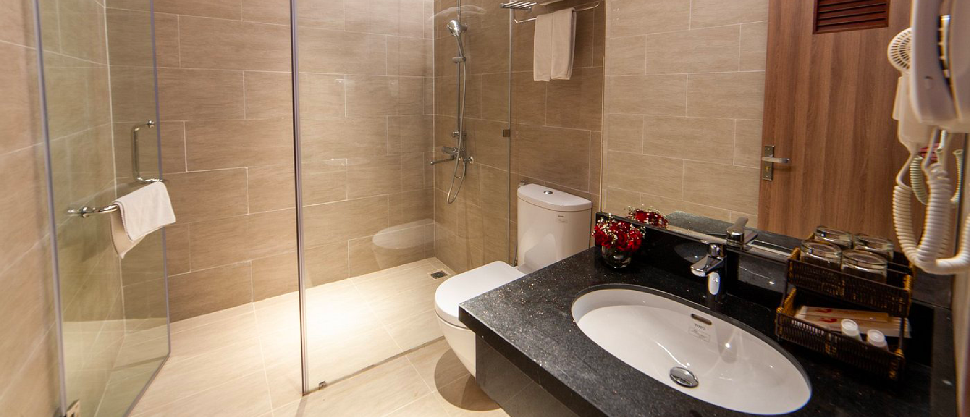 A modern and clean hotel bathroom with a walk-in shower, toilet, and vanity sink.