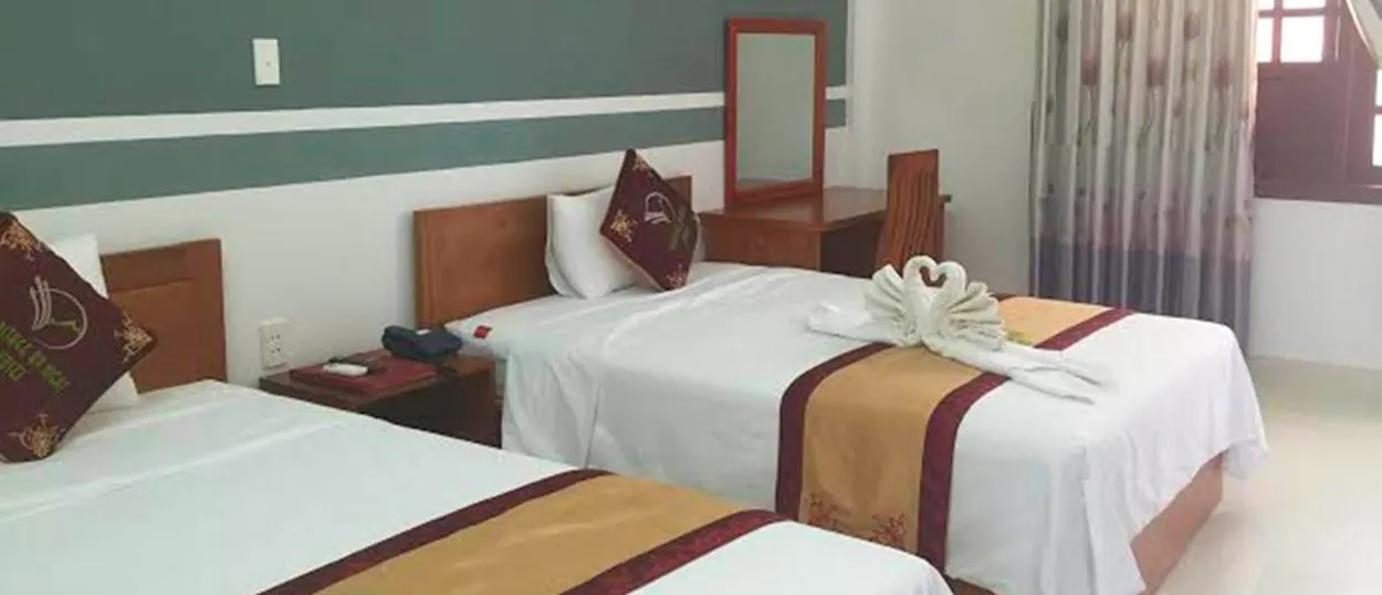 A bright hotel room in Phong Nha with two single beds and a charming towel art swan.