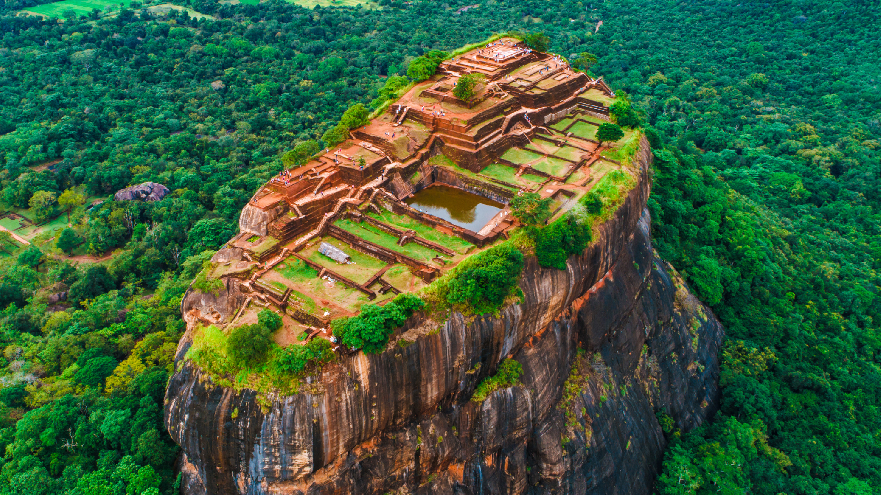 Aerial view of the ancient Sigiriya rock fortress surrounded by lush green jungle in Sri Lanka.