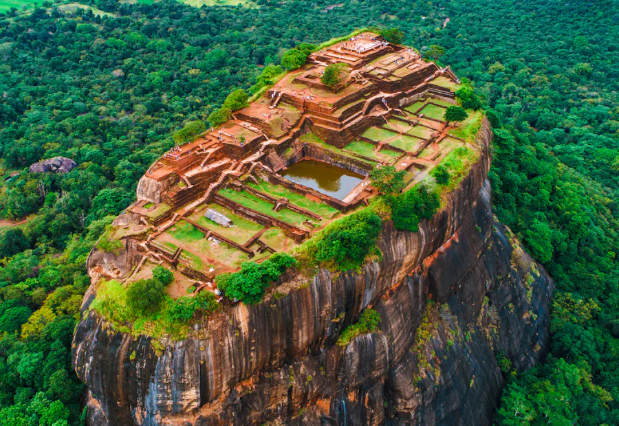 Aerial view of the ancient Sigiriya rock fortress surrounded by lush green jungle in Sri Lanka.