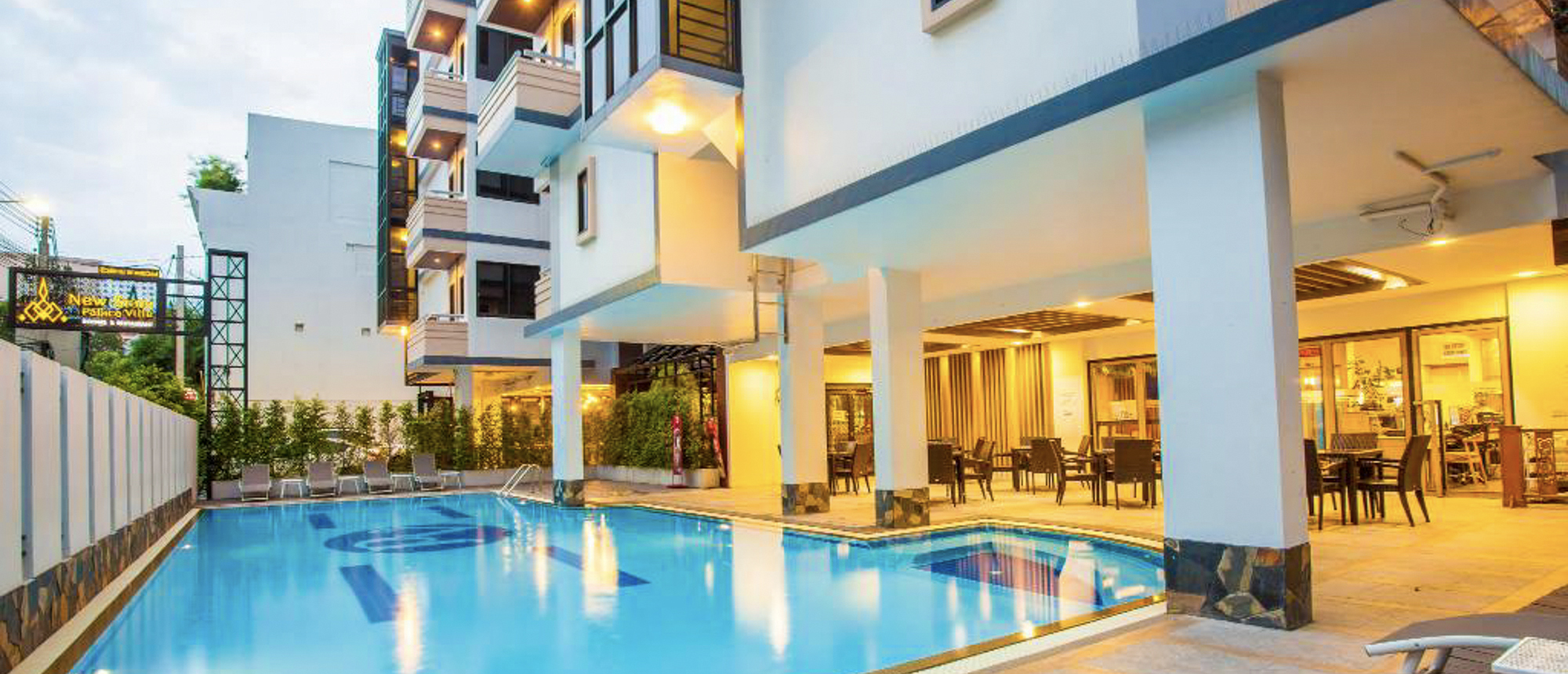 Modern hotel with a bright swimming pool and an inviting outdoor dining area in Thailand.