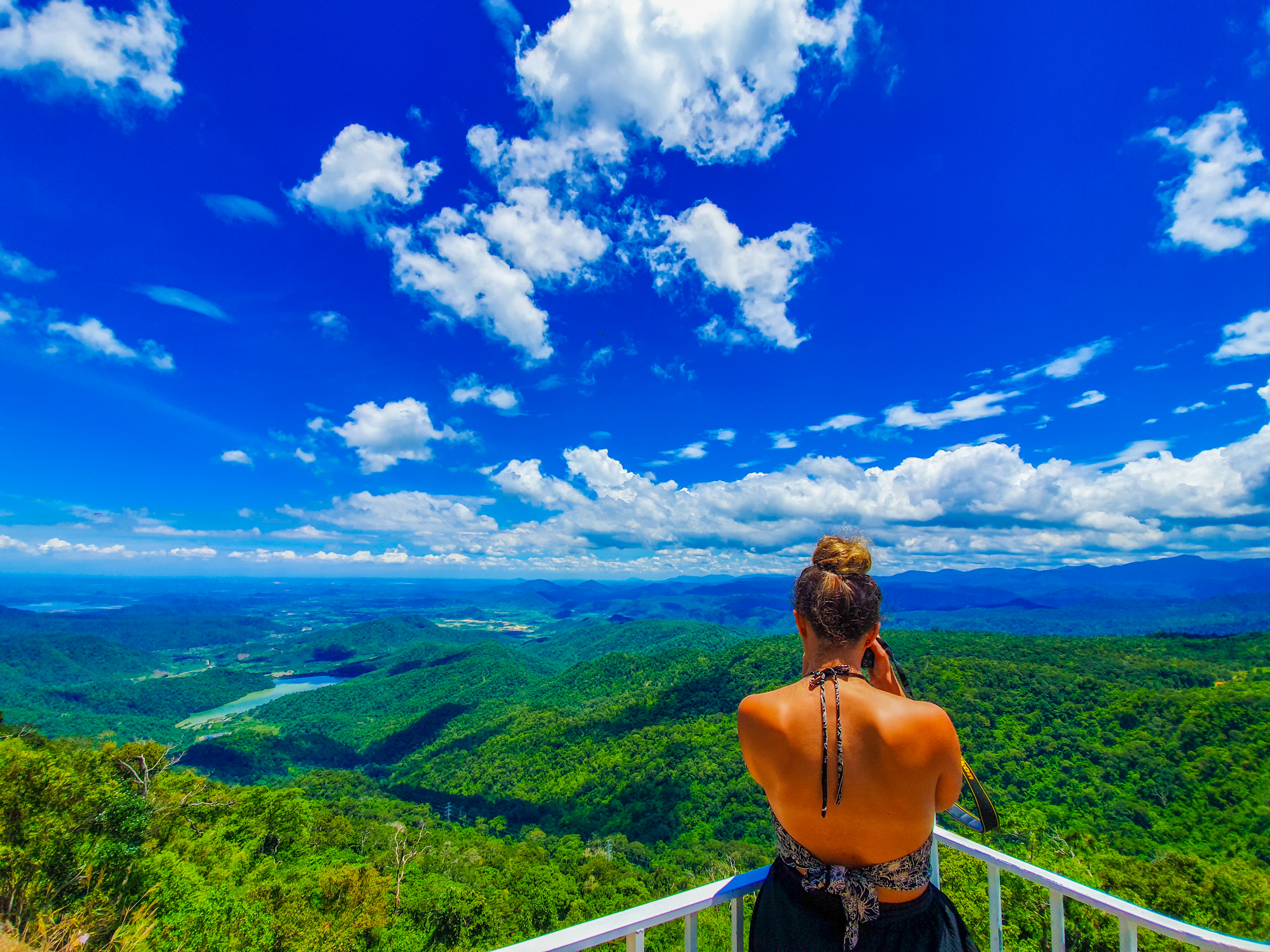 Backpacker gazes at the stunning panoramic view of lush green mountains and valleys in Vietnam.
